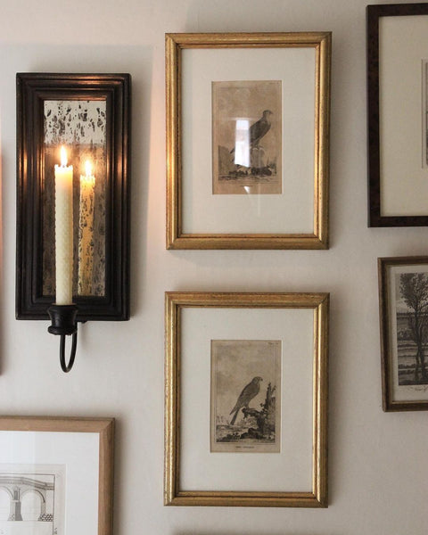 candle and gold picture frames on the wall